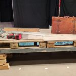 Eine im Rückbau befindliche Brücke aus Holz mit einem darauf stehenden Koffer